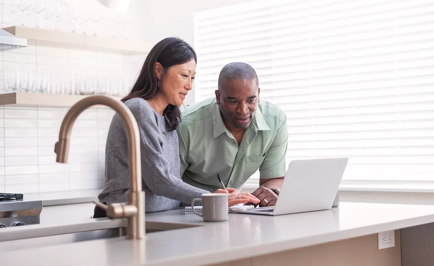  Woman and man standing at kitchen counter viewing laptop computer
