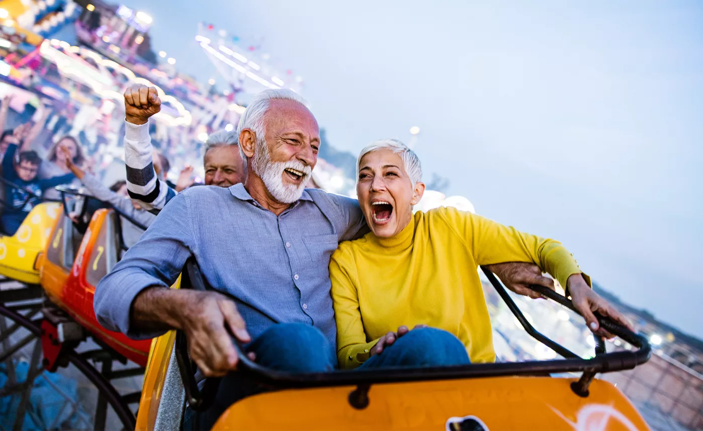  A mature couple laughing while riding a rollercoaster.
