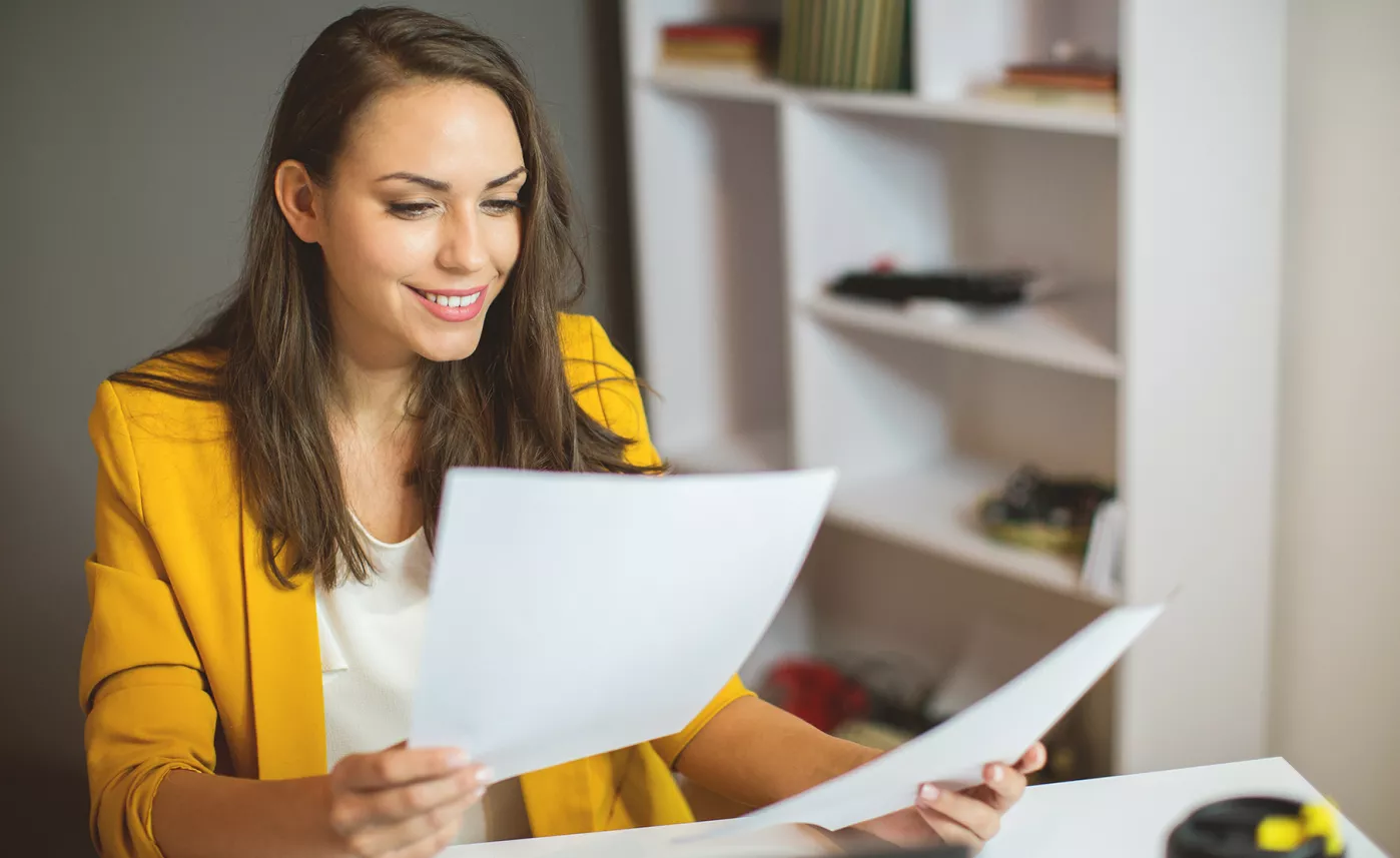  A young woman reviews printed tax documents in her home office.
