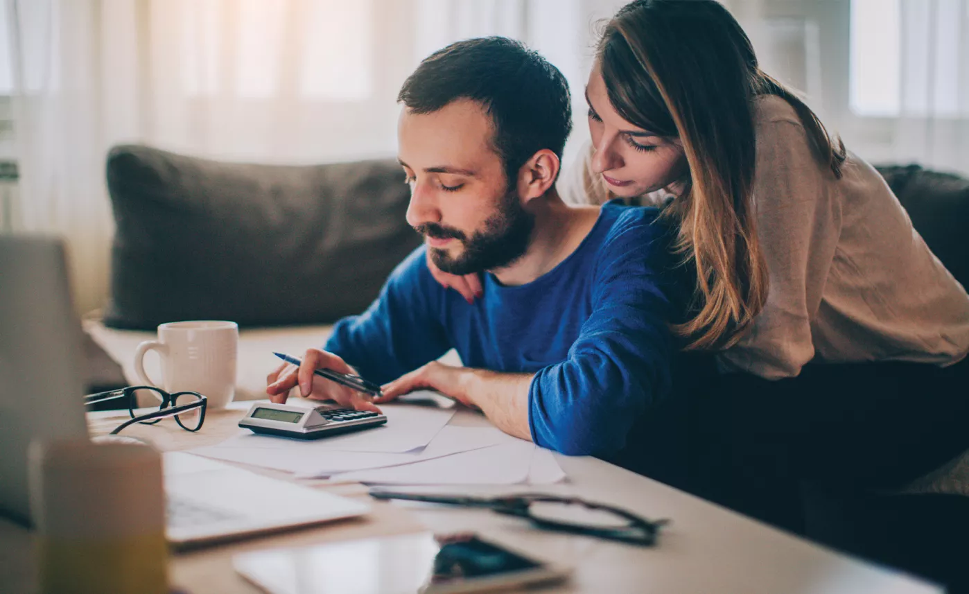  A couple looking at a calculator surrounded by paperwork.
