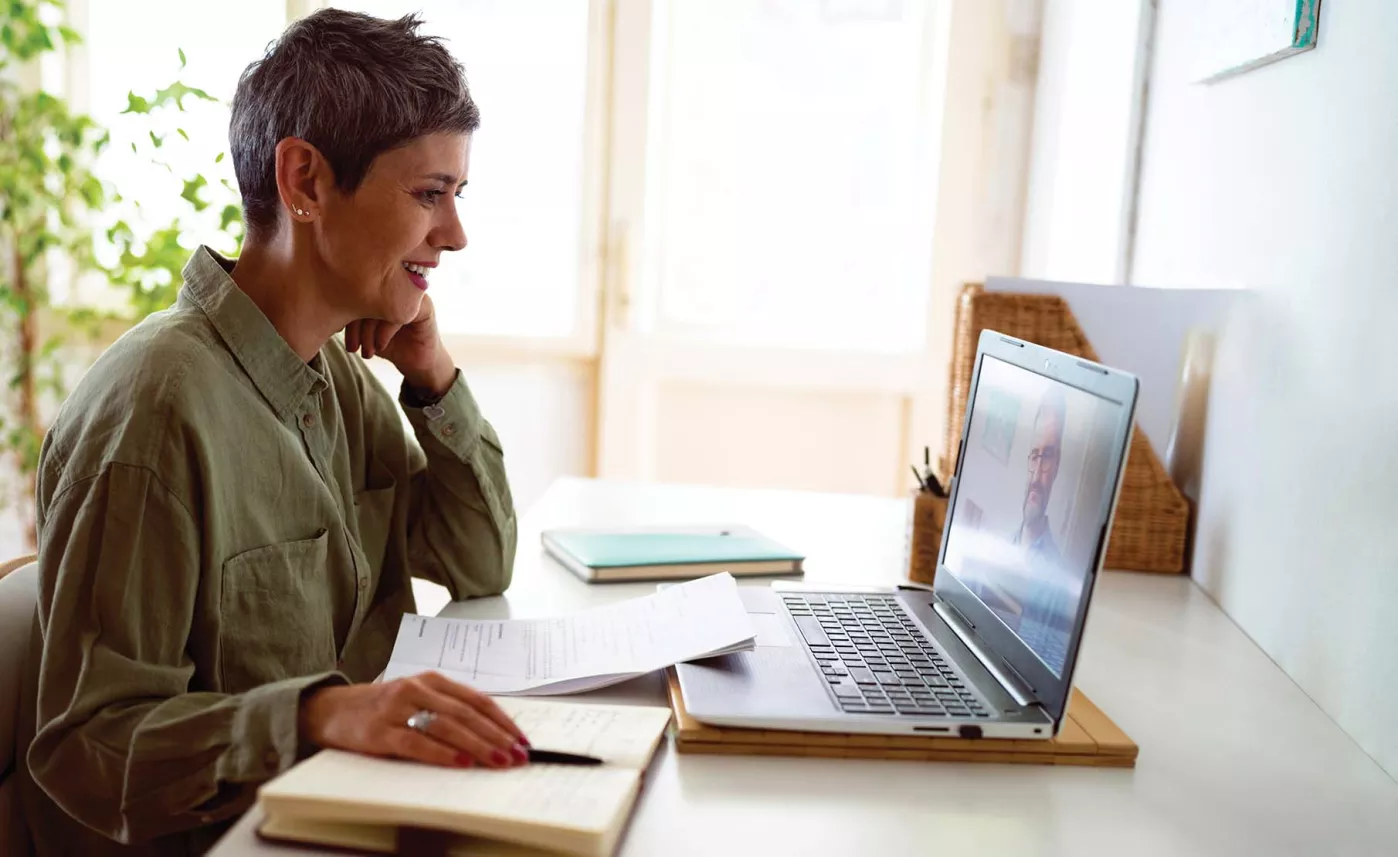  A person on a virtual call with their Financial Advisor, writing notes in a notebook.
