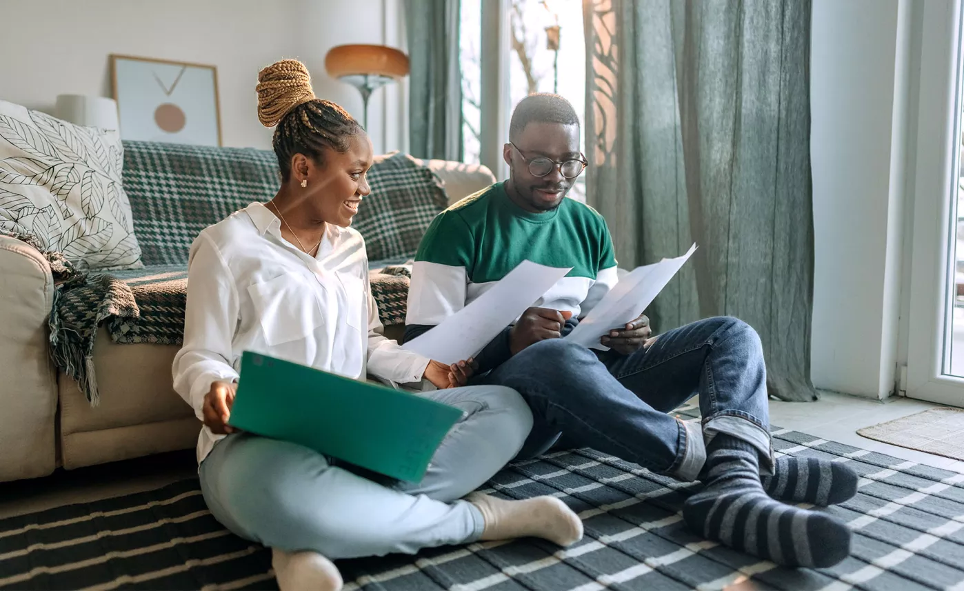  A couple happily smiling and looking at papers together.
