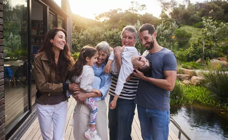  A small family laughing together outside their beautiful home
