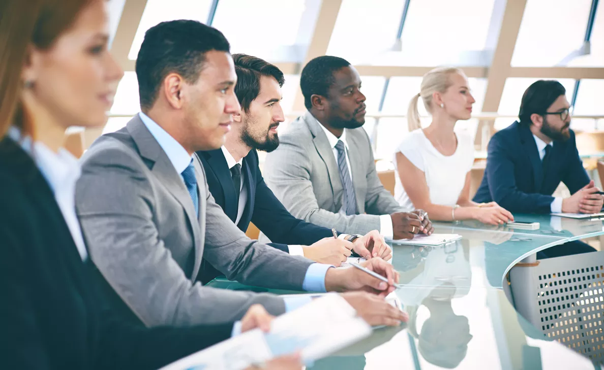 A committee of experts listens to a speaker present information.
