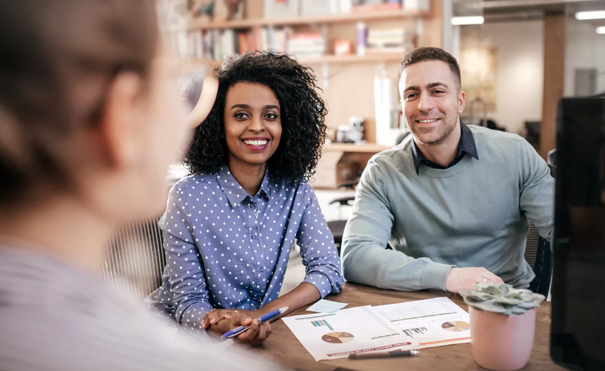  A young couple listens to advice from their financial advisor in a branch office.
