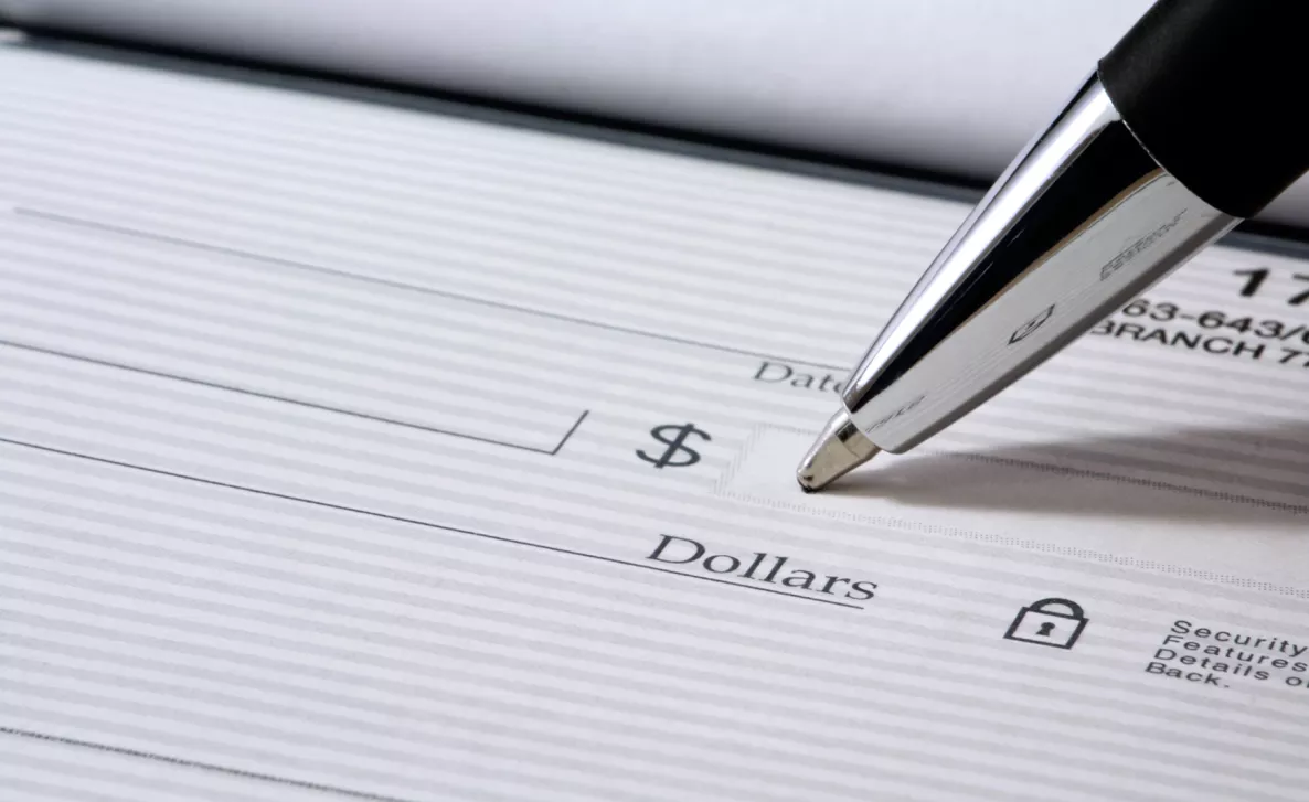  A pen writing in the dollar amount on a check.
