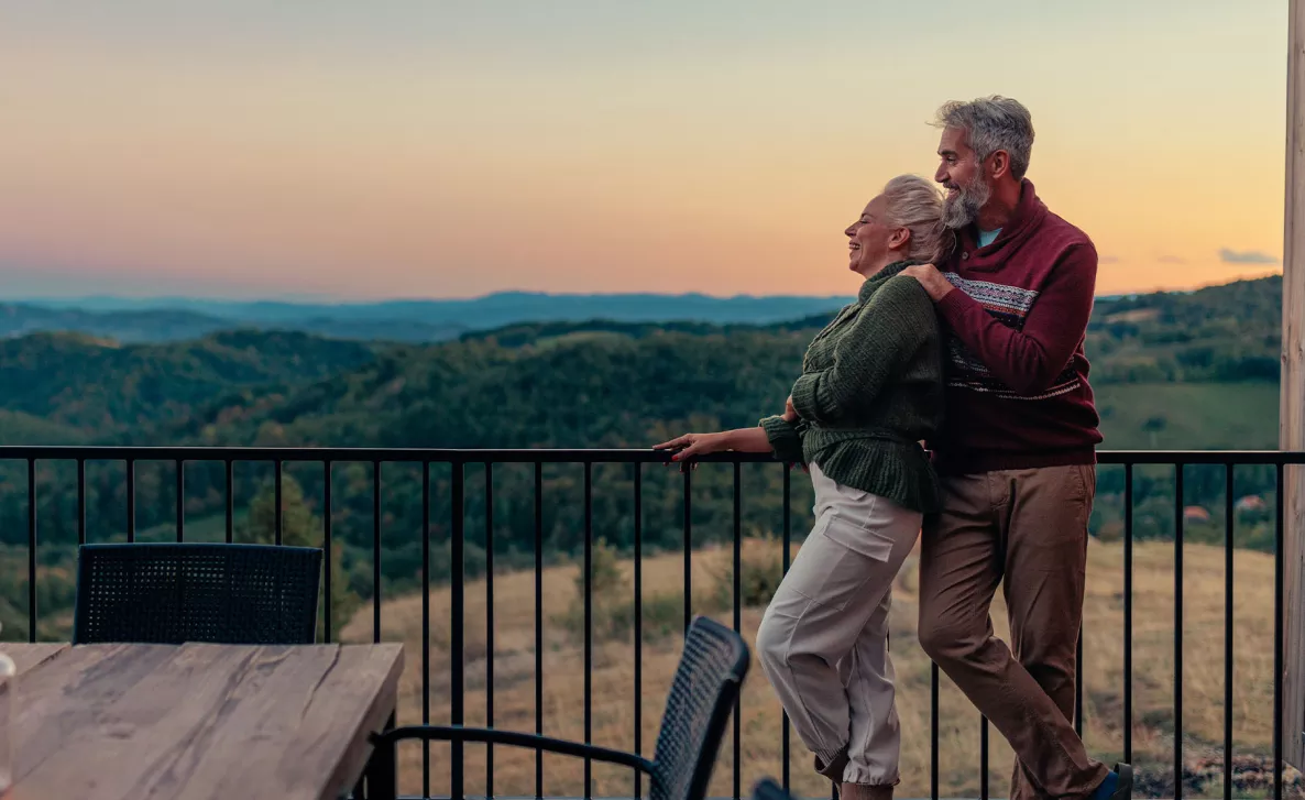  A relaxed couple leaning against a wrought iron fence overlooking a valley
