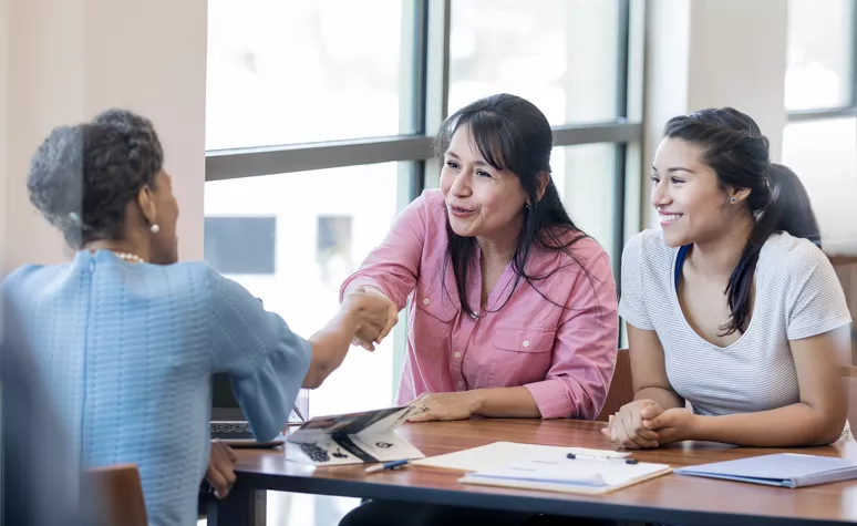 Women shaking hands across a table