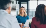 A financial advisor smiles and discusses planning with a middle-aged couple.