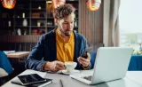 A man reviews FAQs about Edward Jones Online Access on his phone at a cafe.