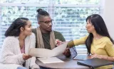 Two young investors listen to an Edward Jones financial advisor provide guidance on bonds and CDs in her branch office.