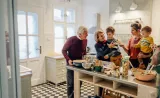 A multi-generational family is gathered in a cozy kitchen